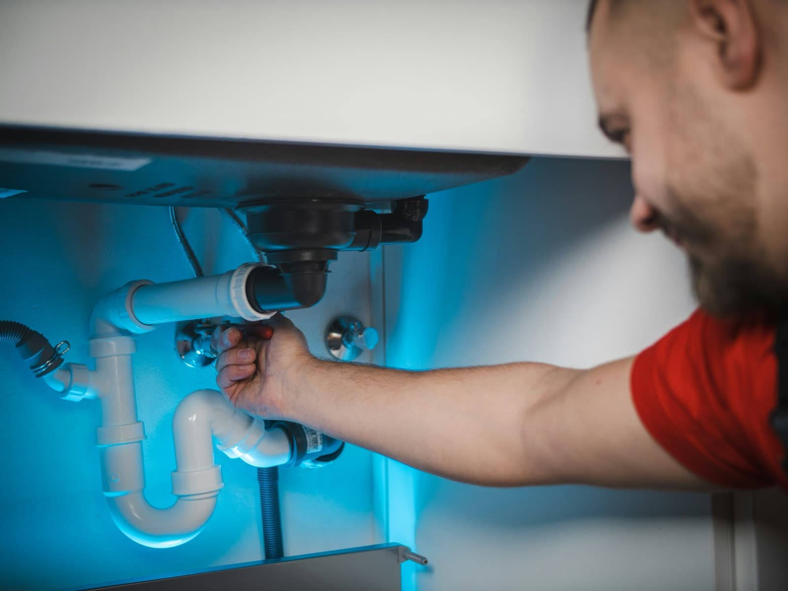 Plumber tightening the PVC P-trap under a kitchen sink